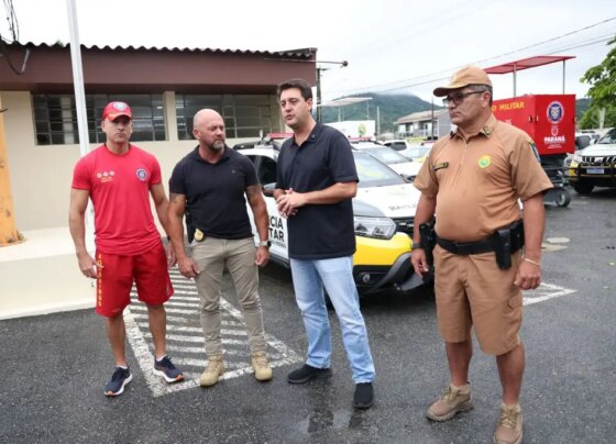 Foto de autoridades locais reunidas em frente a veículos de segurança, discutindo estratégias e ações para a segurança pública. Governador anuncia concurso público com 2.600 vagas para PM e Corpo de Bombeiros