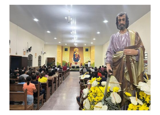 Imagem de uma celebração religiosa em uma igreja, onde destaca-se uma estátua de um santo ao primeiro plano, flores e um mural religioso ao fundo. 27.ª Festa em louvor a São José Operário acontecerá em Paranaguá