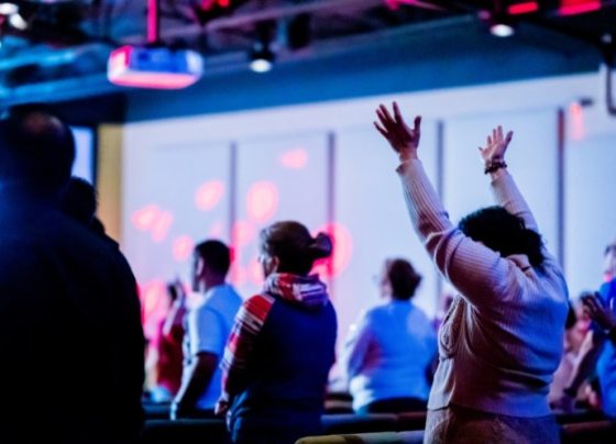 Pessoas louvando durante culto em igreja (Foto: Canva Pro)