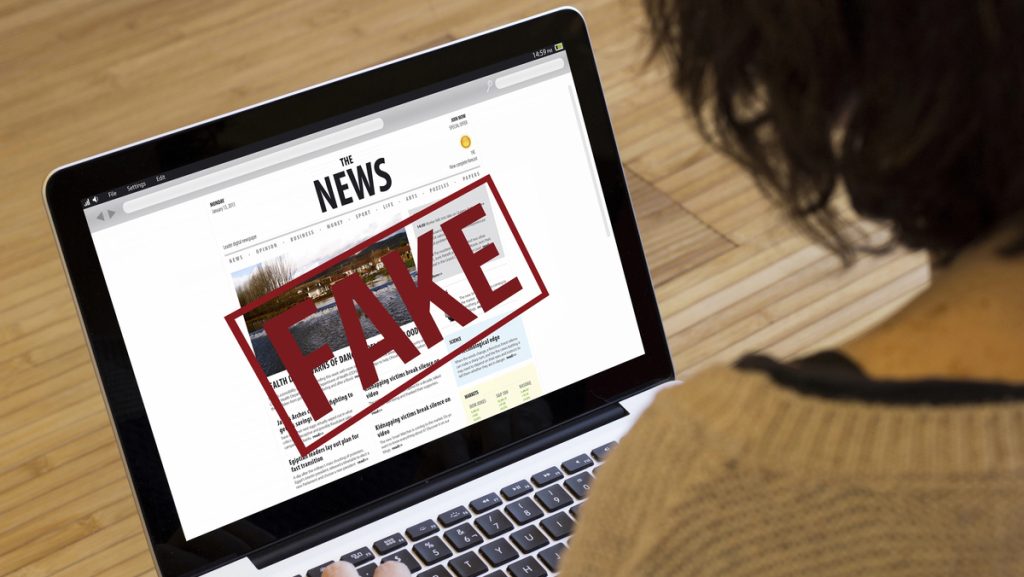 mulher olha fake news em computador