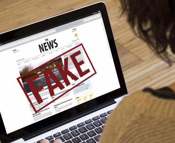 mulher olha fake news em computador