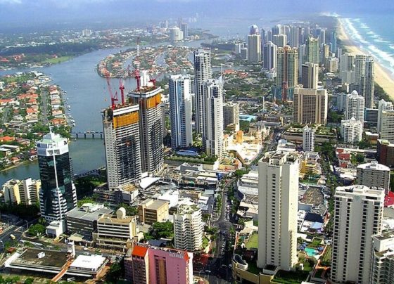 Vista aérea de Gold Coast, na Austrália, com prédios altos próximos à praia, canal com casas ao redor e faixa extensa de areia ao lado do mar