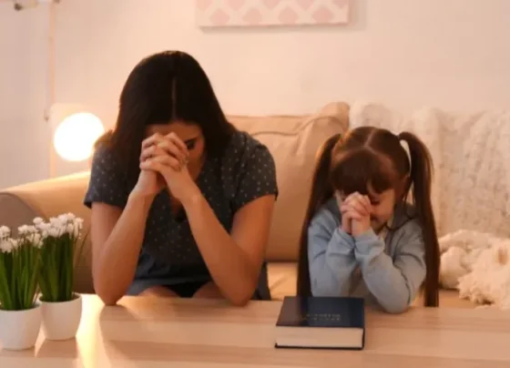 Mãe e filha orando com uma Bíblia na mesa (Foto: Canva Pro)